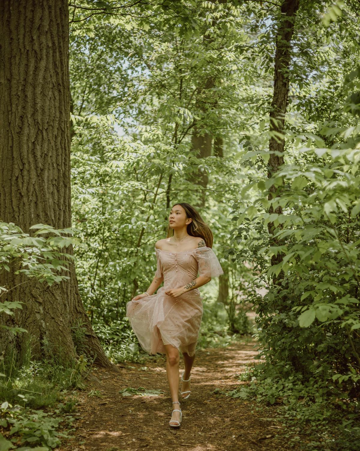 Woman walking mindfully through a sunlit forest path, the kind of active movement that complements a breathing meditation practice by grounding attention in the body